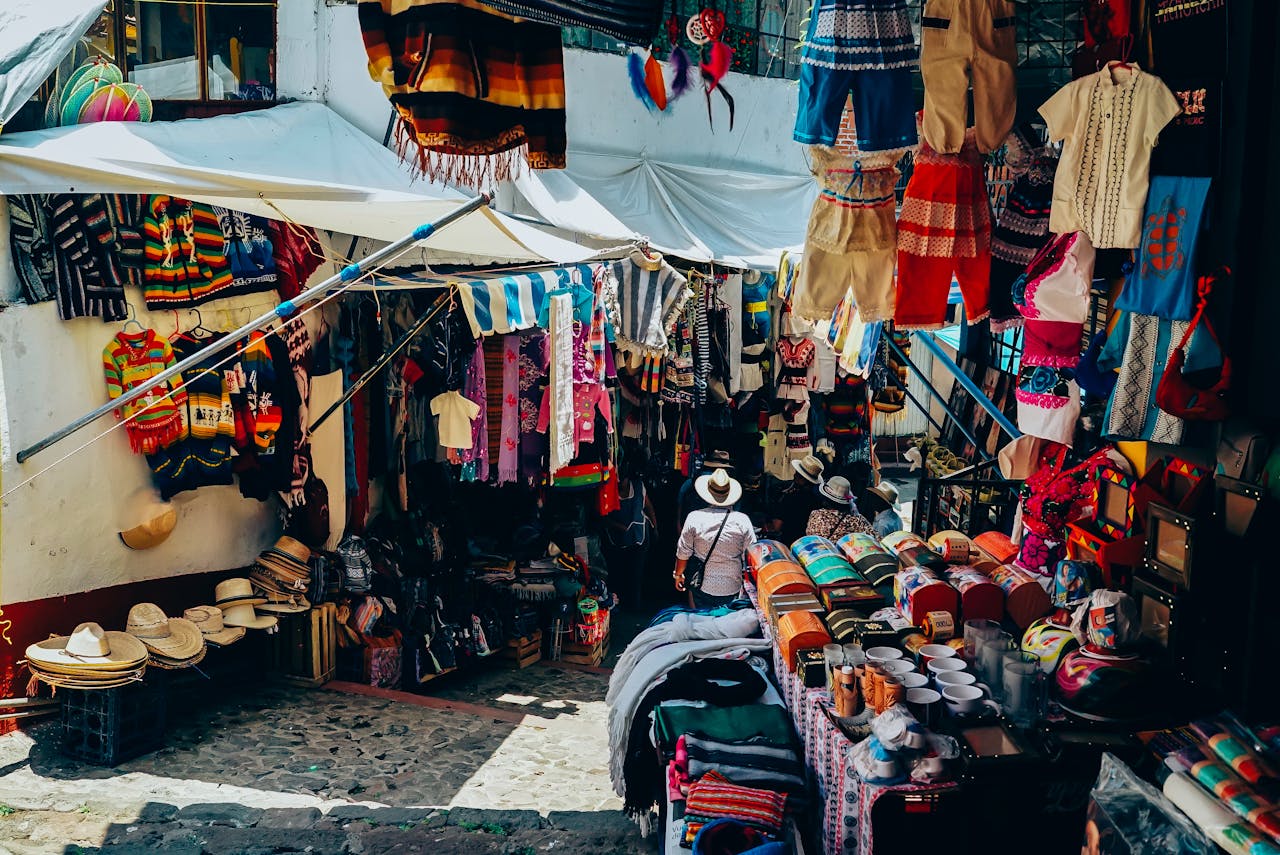 portfolio-02 A bustling outdoor market stall showcasing traditional clothing and crafts in an inviting atmosphere.